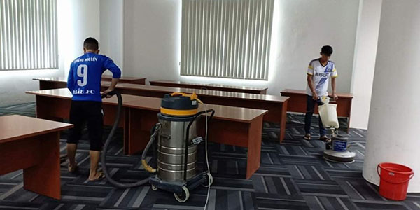 Nhân viên dịch vụ vệ sinh đang tiến hành giặt thảm văn phòng